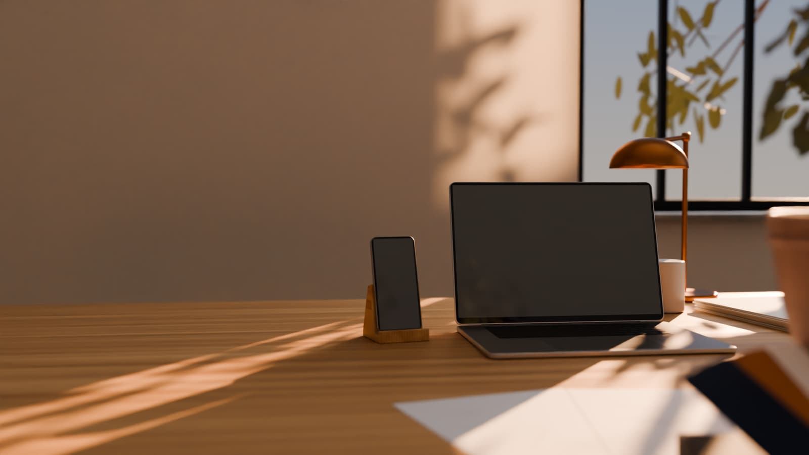 Een ontwerpstudio in namiddaglicht, 3D-render: een opengeklapte laptop en een telefoon in een houten standaard op een eiken bureau, een koperen bureaulamp, een raam met gevlekt licht op de gestucte wand, en onscherp op de voorgrond kleurstalen en schetsen.